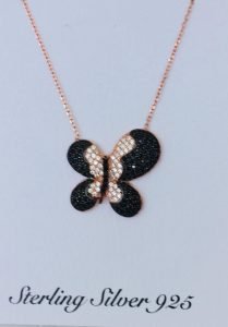 black butterfly necklace hanging on the white wall