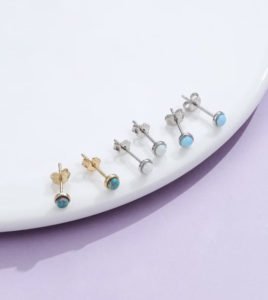 three pairs of australian opal silver earrings displayin on a white platform