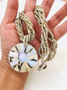 woman holding abalone necklace