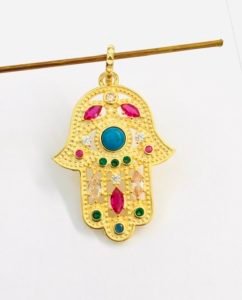 a stick holding hand of hamsa with natural multi stones in a white background