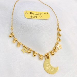 a half moon necklace is displayed in the gray background color