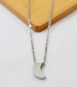 silver moon necklace with chain on a wood table